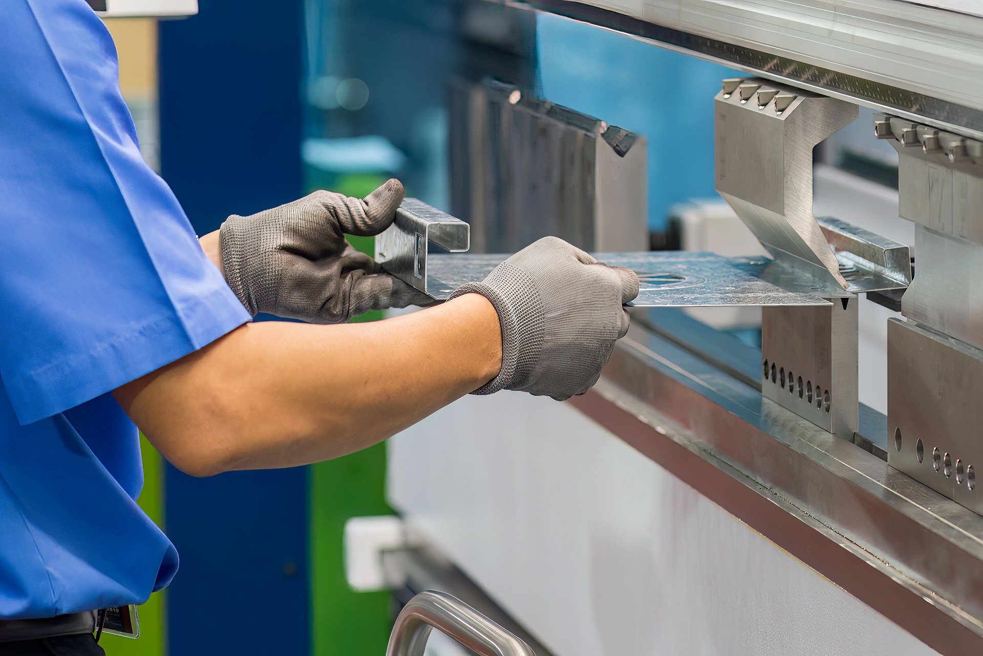 Close up the bending machine operator hold the sheet metal parts and  wear safety  glove.